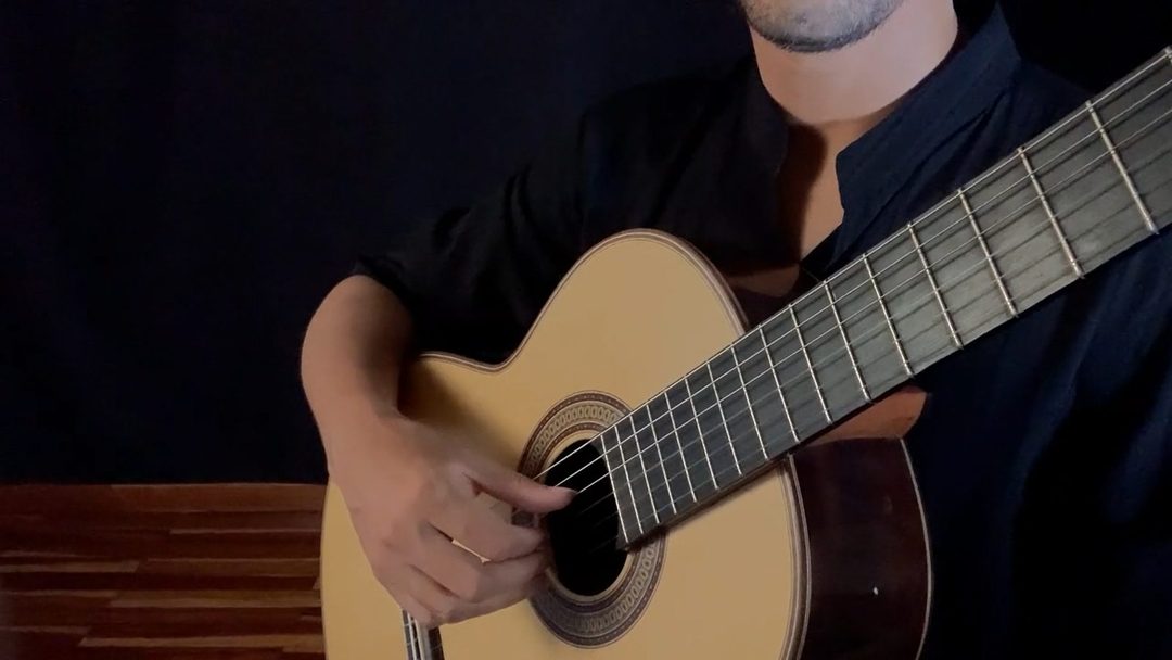 Close dos dedos da mão direita tocando as cordas do violão perto do captador.