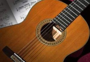 Violão apoiado sobre páginas de uma partitura musical