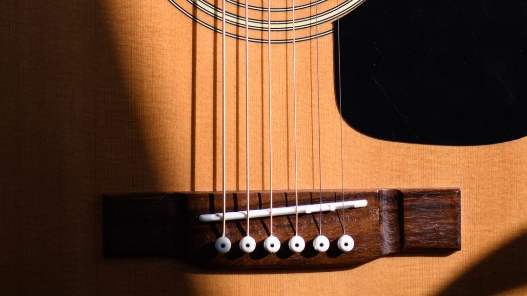 Violão acústico visto de frente, destacando o tampo e a madeira do instrumento.